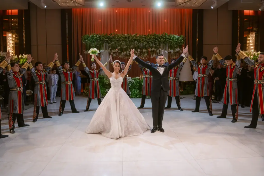 Bride and groom raising hands together at The Landmark, flanked by a ceremonial honor guard in red uniforms