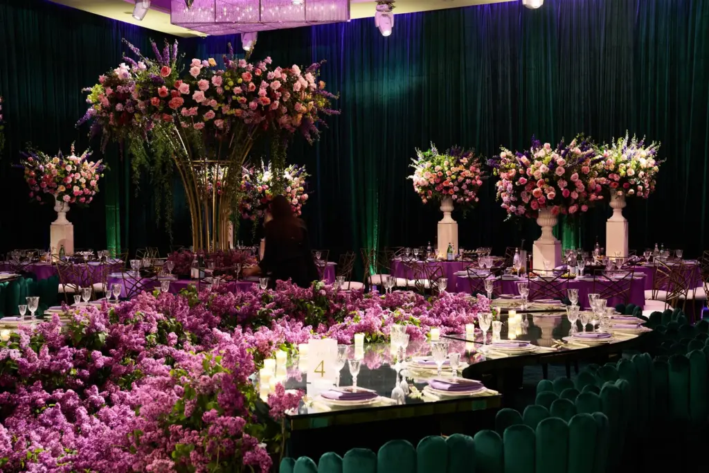 Wedding reception ballroom with tall floral centerpieces, purple linens, and lilac table runners
