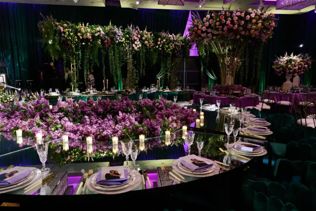 Reception hall with hanging floral installations above a lilac flower table runner