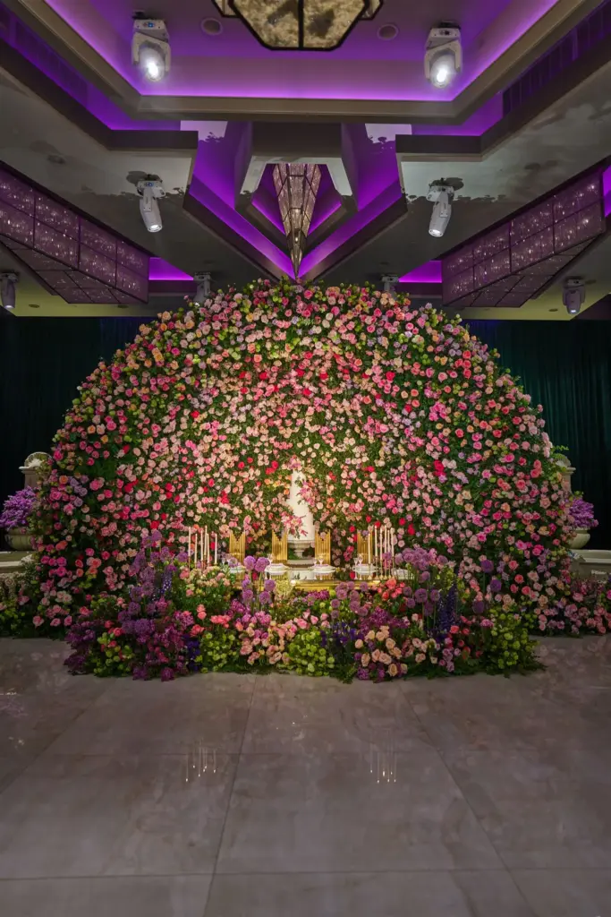 Domed floral backdrop with a wedding cake displayed beneath pink and white roses