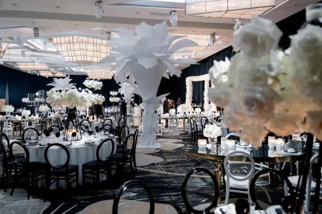 Reception hall decorated with oversized white paper flower sculptures and round tables
