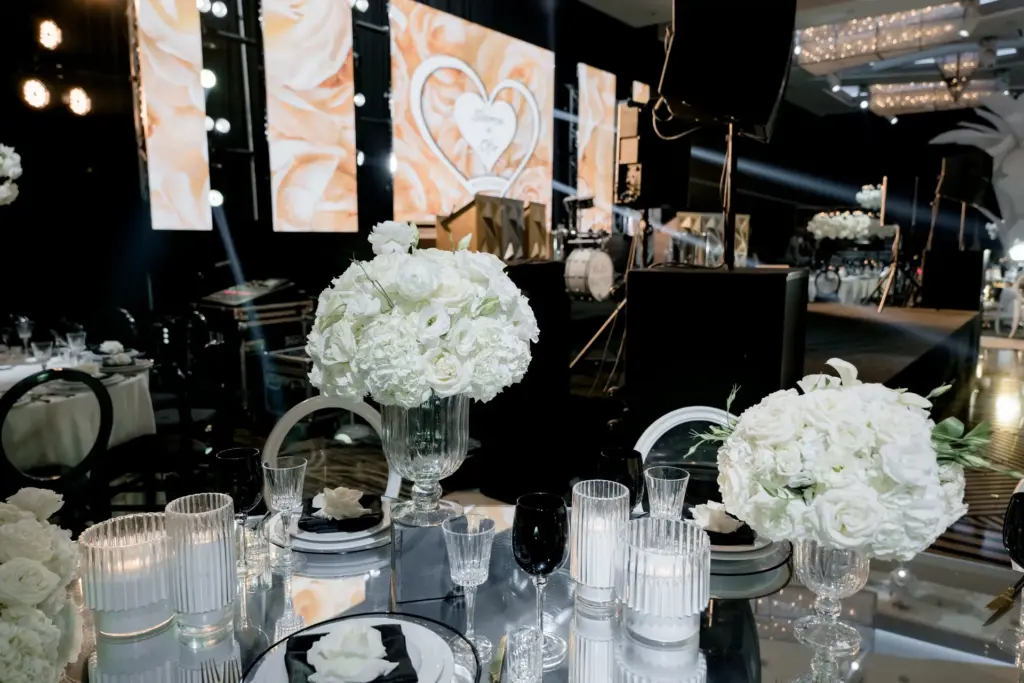 Stage with heart-shaped video screens and a white floral centerpiece at a wedding reception